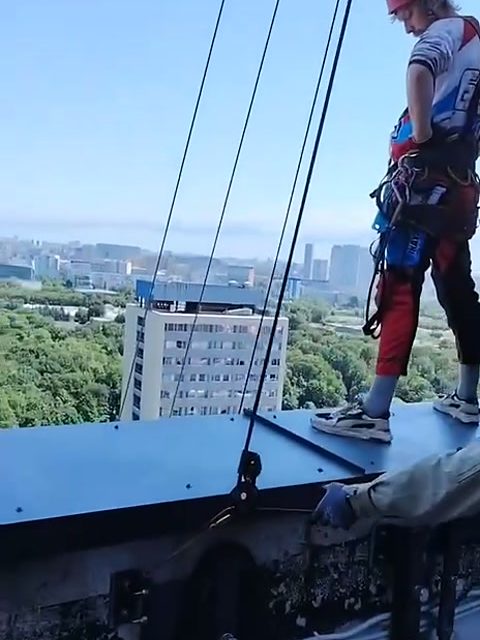 Промышленный альпинист на парапете высотки у точки подъёма