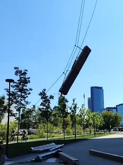 Длинную коробку поднимают альпинисты на верёвках вдоль фасада